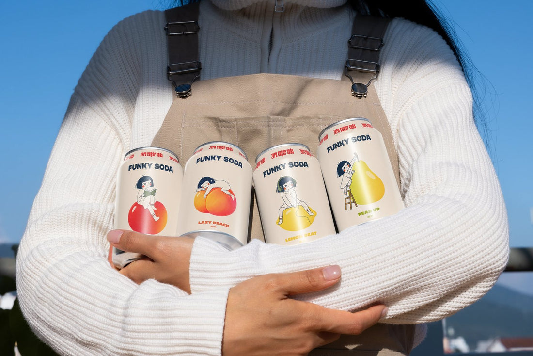 Four Funky Soda zero sugar cans in Apple Tale, Lazy Peach, Lemon Beat and Pear Up held in both arms