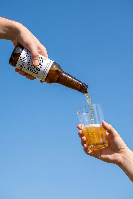 Beer bottle mockup pouring beverage into clear glass outdoors