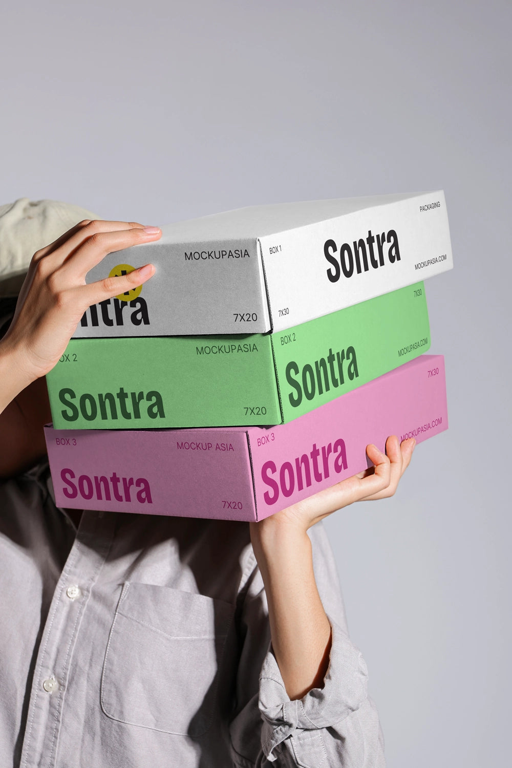 Stacked box packaging mockup with colorful cardboard boxes held in hands close up view