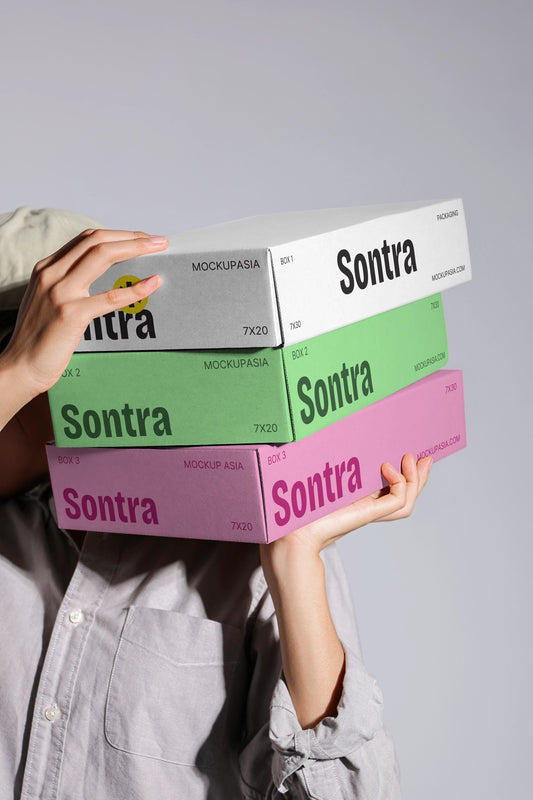 Stacked box packaging mockup with colorful cardboard boxes held in hands close up view