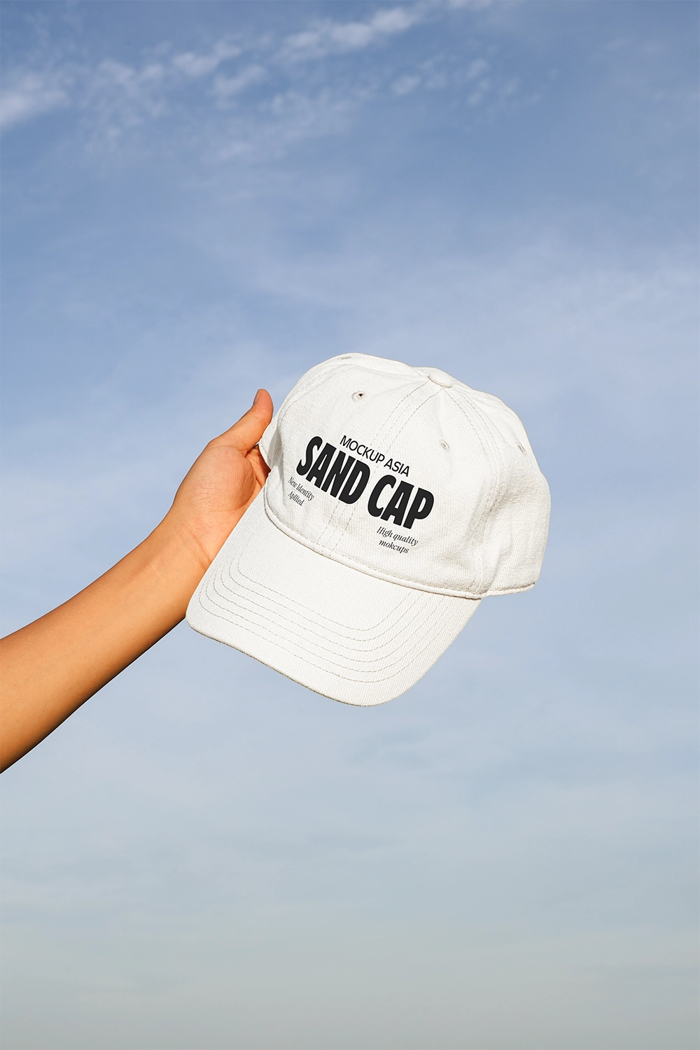baseball cap mockup held in hand with clear sky background and natural daylight
