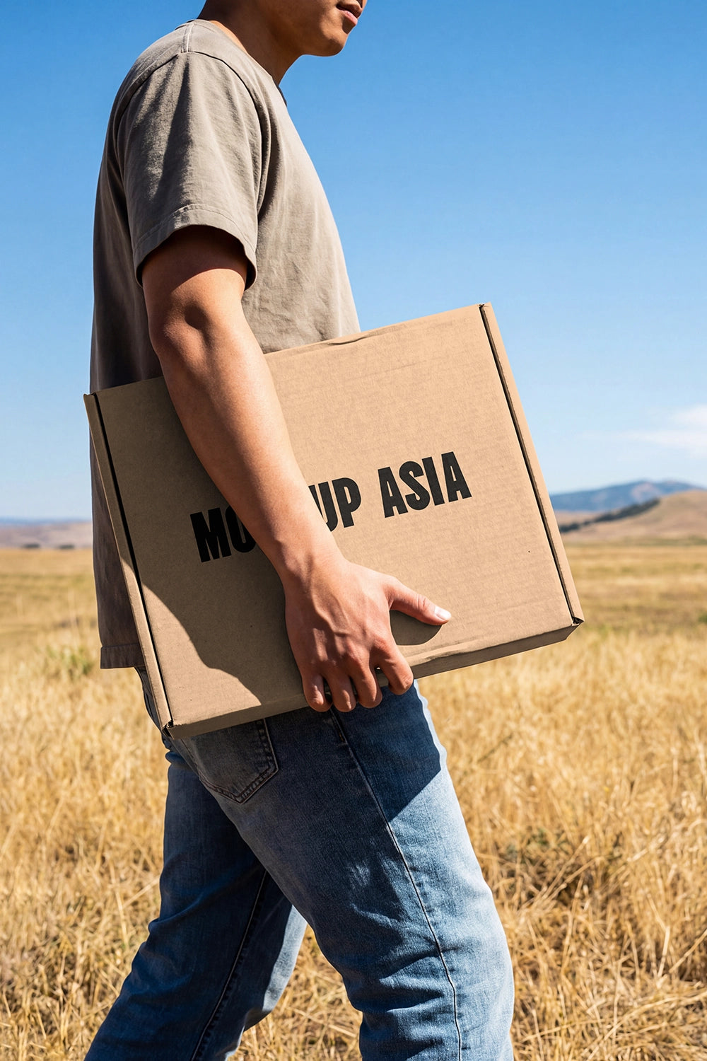 minimal cardboard box mockup in hand with outdoor scenery and clear sky background