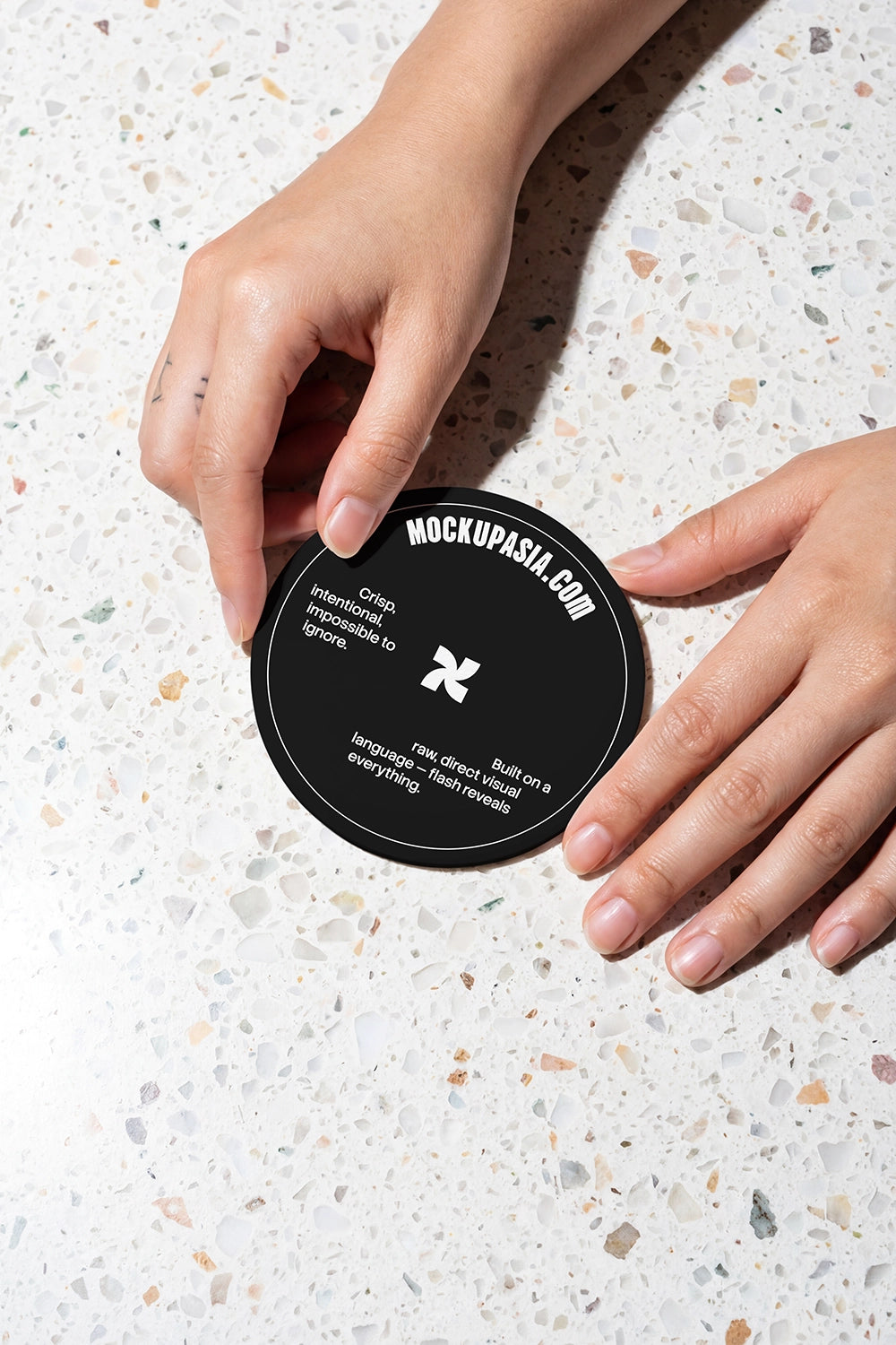 round print mockup with hands placing coaster on terrazzo surface under flash
