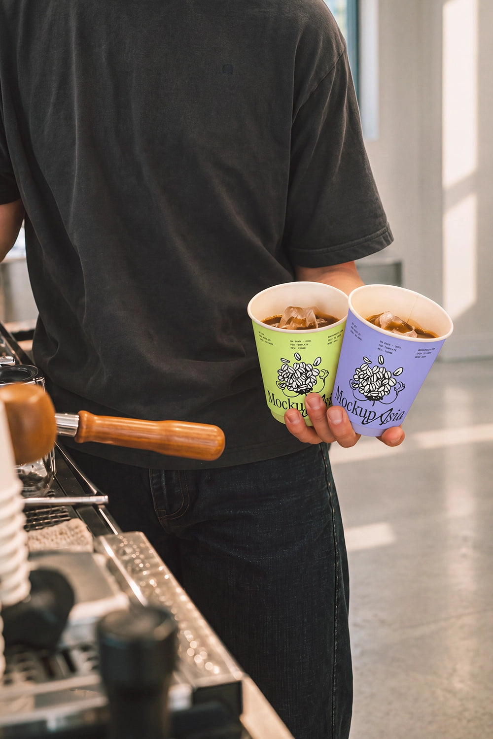 Two paper coffee cup mockups beside espresso machine in café