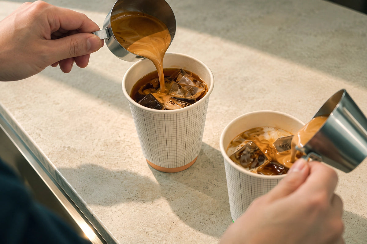 Iced latte cup mockup PSD barista pouring espresso into paper cups
