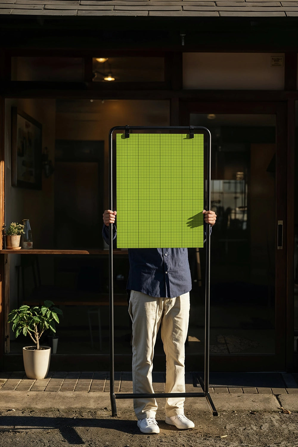 portable sidewalk poster mockup for coffee shop with person holding sign and warm lighting