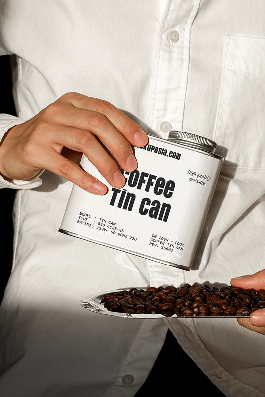 coffee tin can mockup held in hand pouring coffee beans, realistic packaging presentation