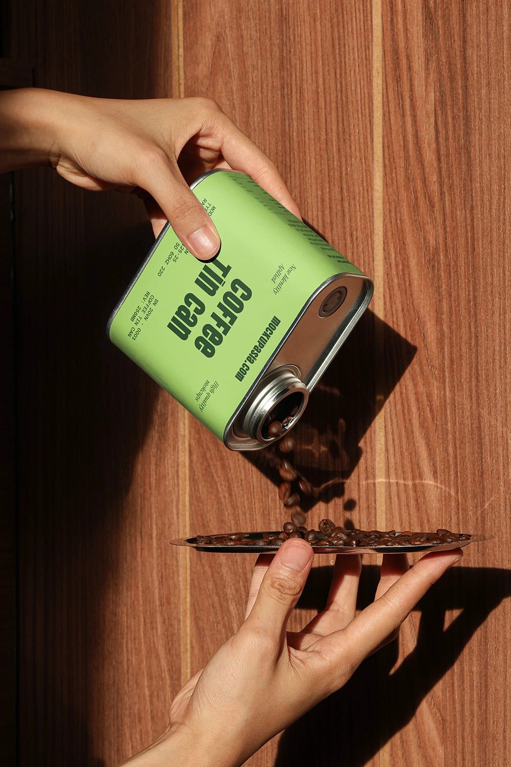 metal coffee tin can mockup with pouring beans and hand interaction, modern branding presentation