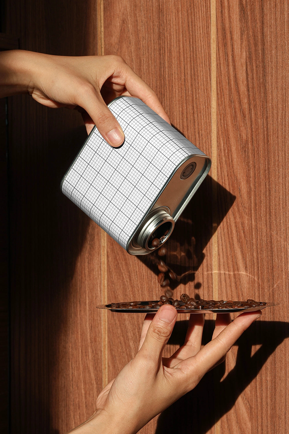 coffee tin packaging mockup with beans falling into tray, dramatic shadow and wood texture