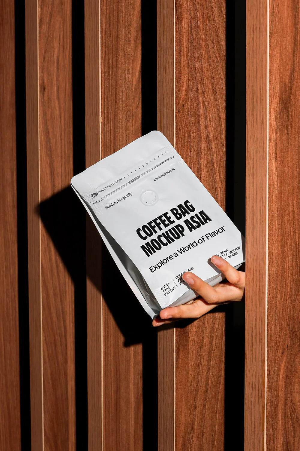 coffee pouch mockup held in hand against wooden wall, strong sunlight and shadows