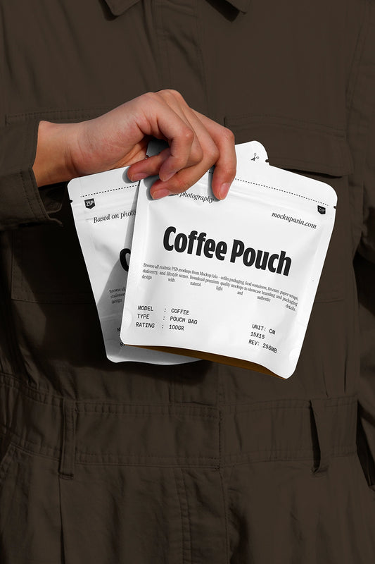 Handheld coffee pouch mockup with white packaging against dark clothing background
