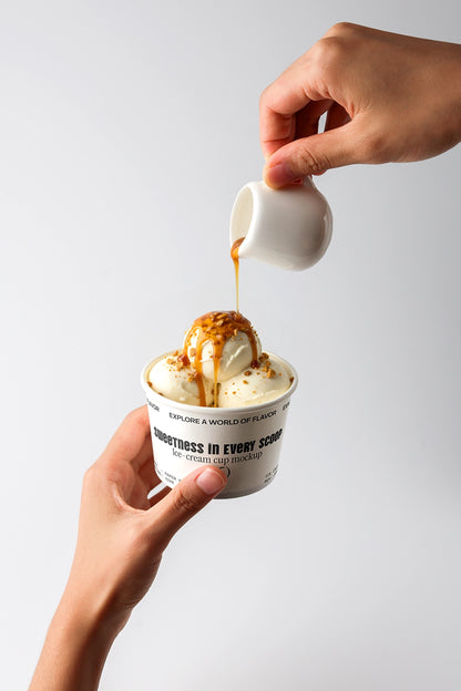 Ice cream cup mockup with caramel sauce pouring over vanilla scoop held in hands