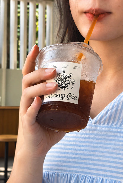 Plastic cup sticker mockup PSD woman sipping iced coffee with straw