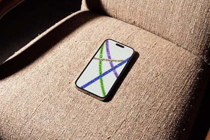 A smartphone lying on a textured beige upholstered chair in warm sunlight, with a white screen showing a colorful abstract graphic and partial text.