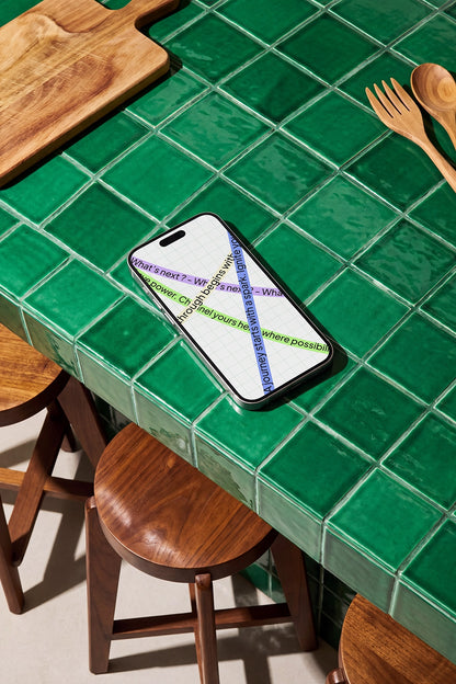 Realistic iPhone mockup resting on a glossy green tiled table
