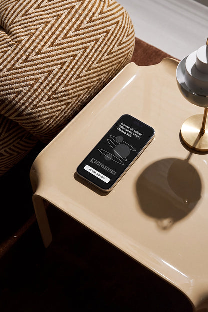 Smartphone PSD mockup beside a textured lounge chair and table lamp