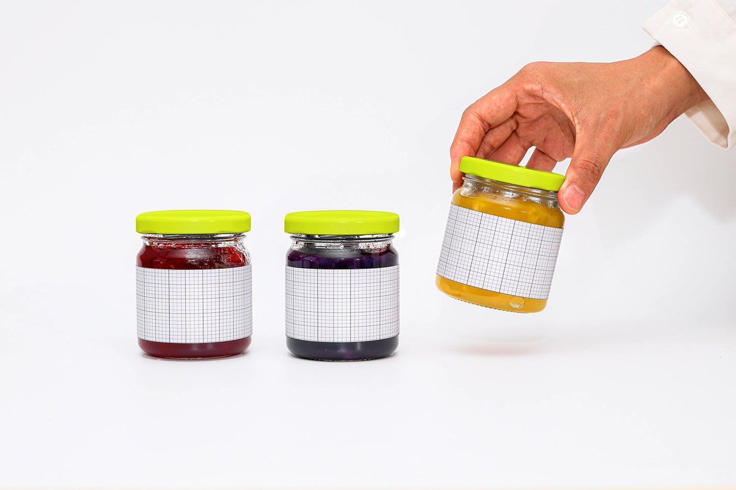 Food branding mockup with three jam jars in different colors and one held in hand