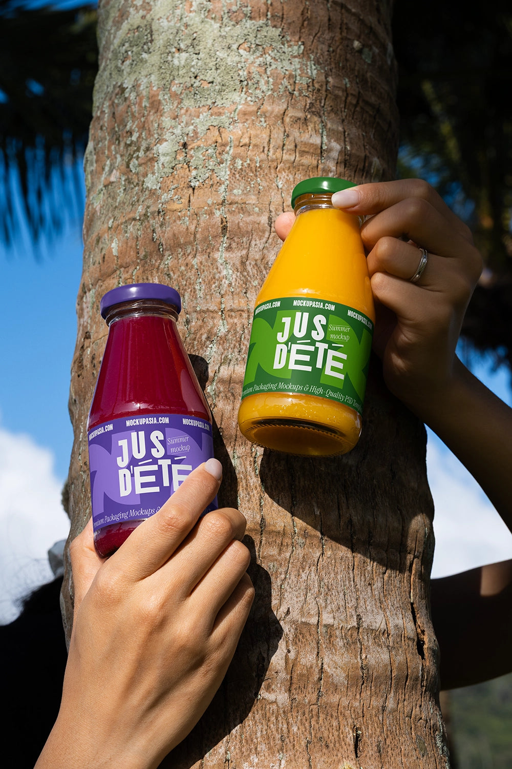 Glass juice bottle mockup pair handheld outdoor realistic beverage packaging PSD