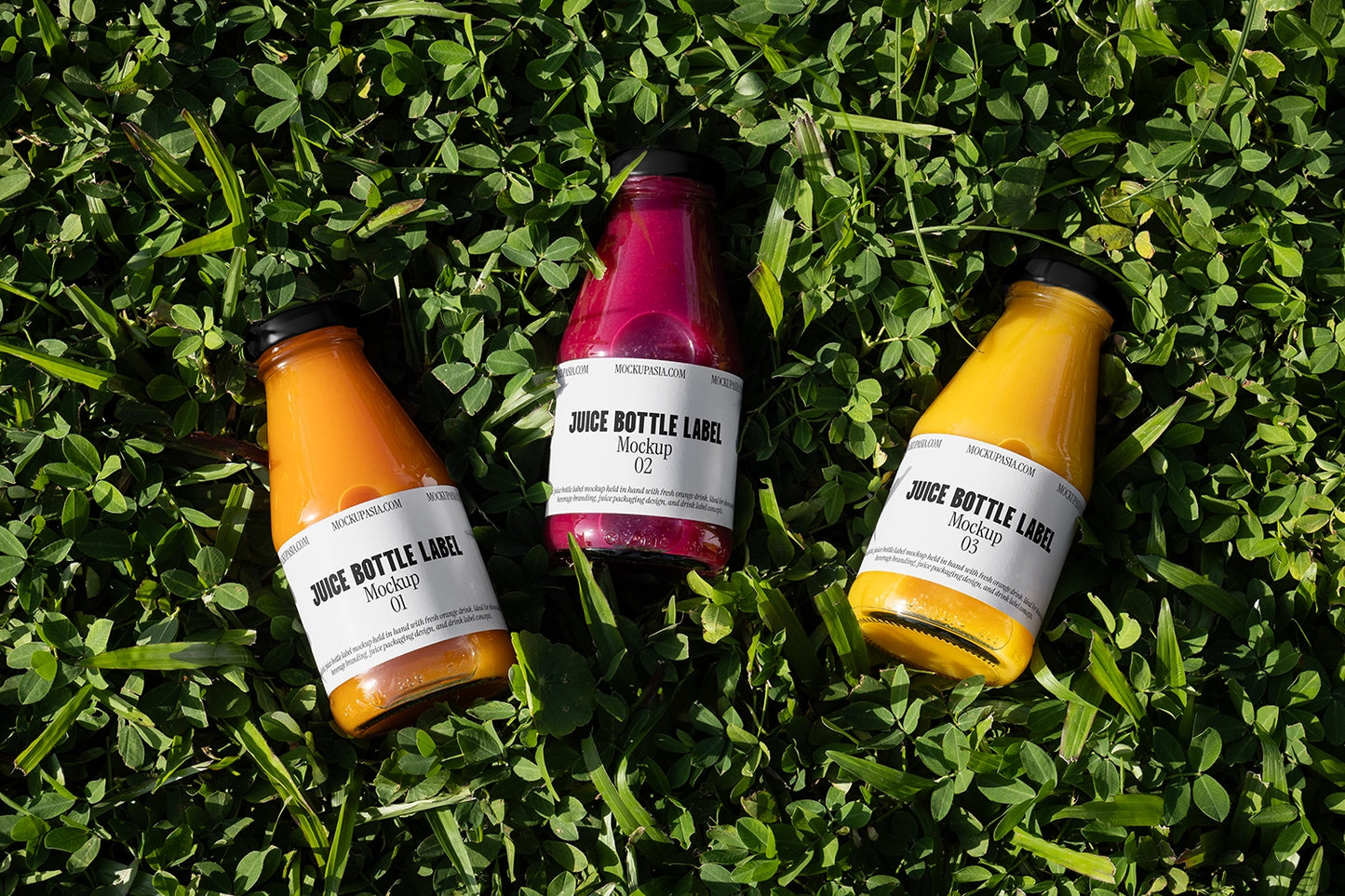 juice bottle label mockup with three glass bottles on green grass