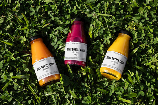 juice bottle label mockup with three glass bottles on green grass
