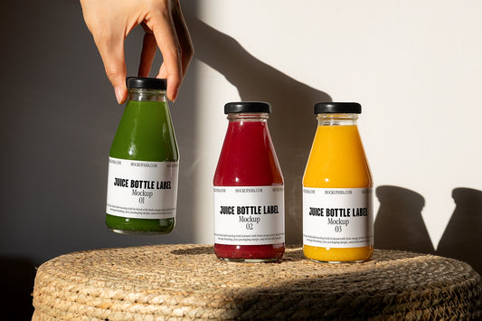 Juice bottle mockup with three glass bottles and hand holding green juice in natural sunlight