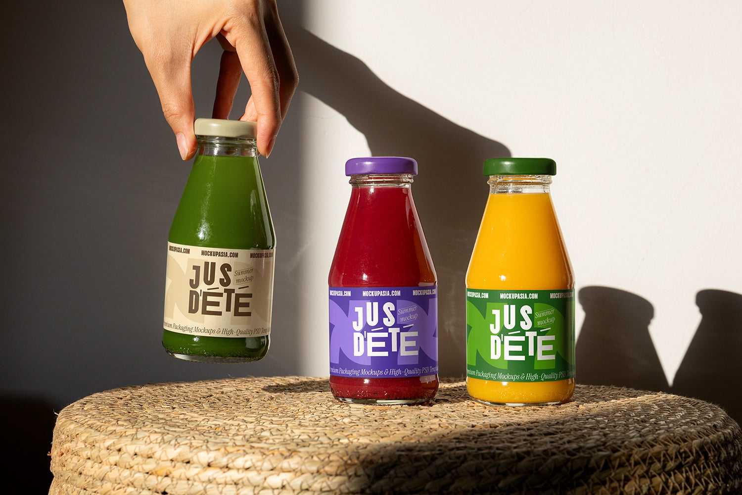 Glass juice bottle label mockup set with green, red and orange drinks on textured surface