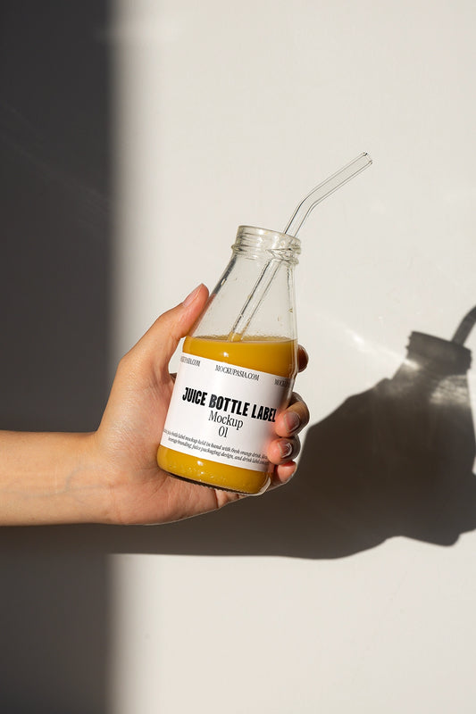 juice bottle label mockup with glass bottle and straw handheld scene