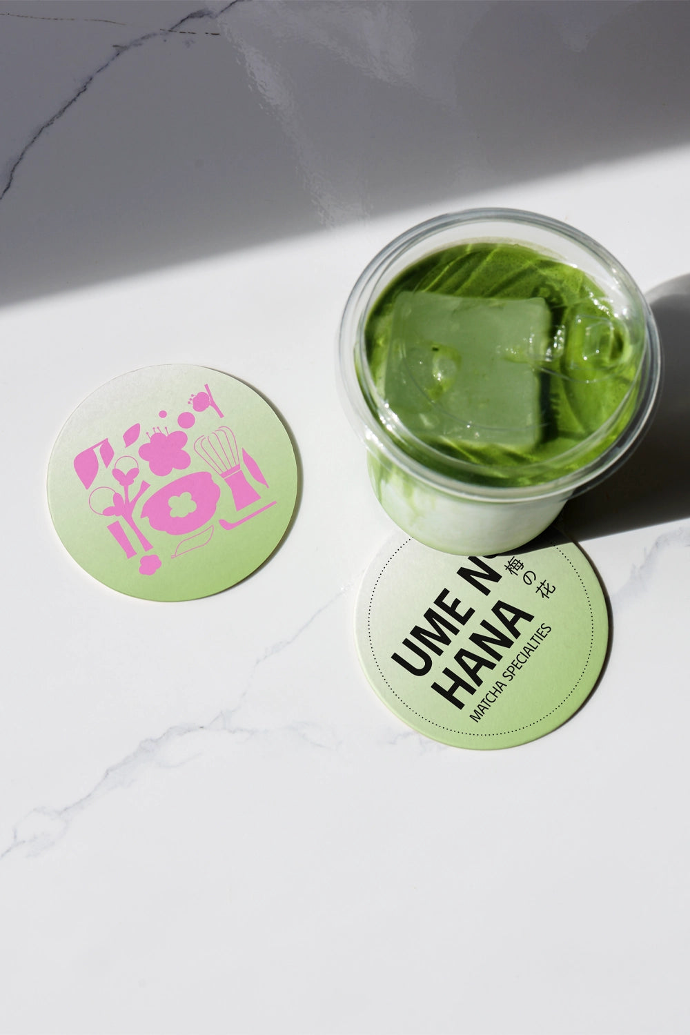matcha drink mockup top view with glass jar and ice, branding coasters on marble surface