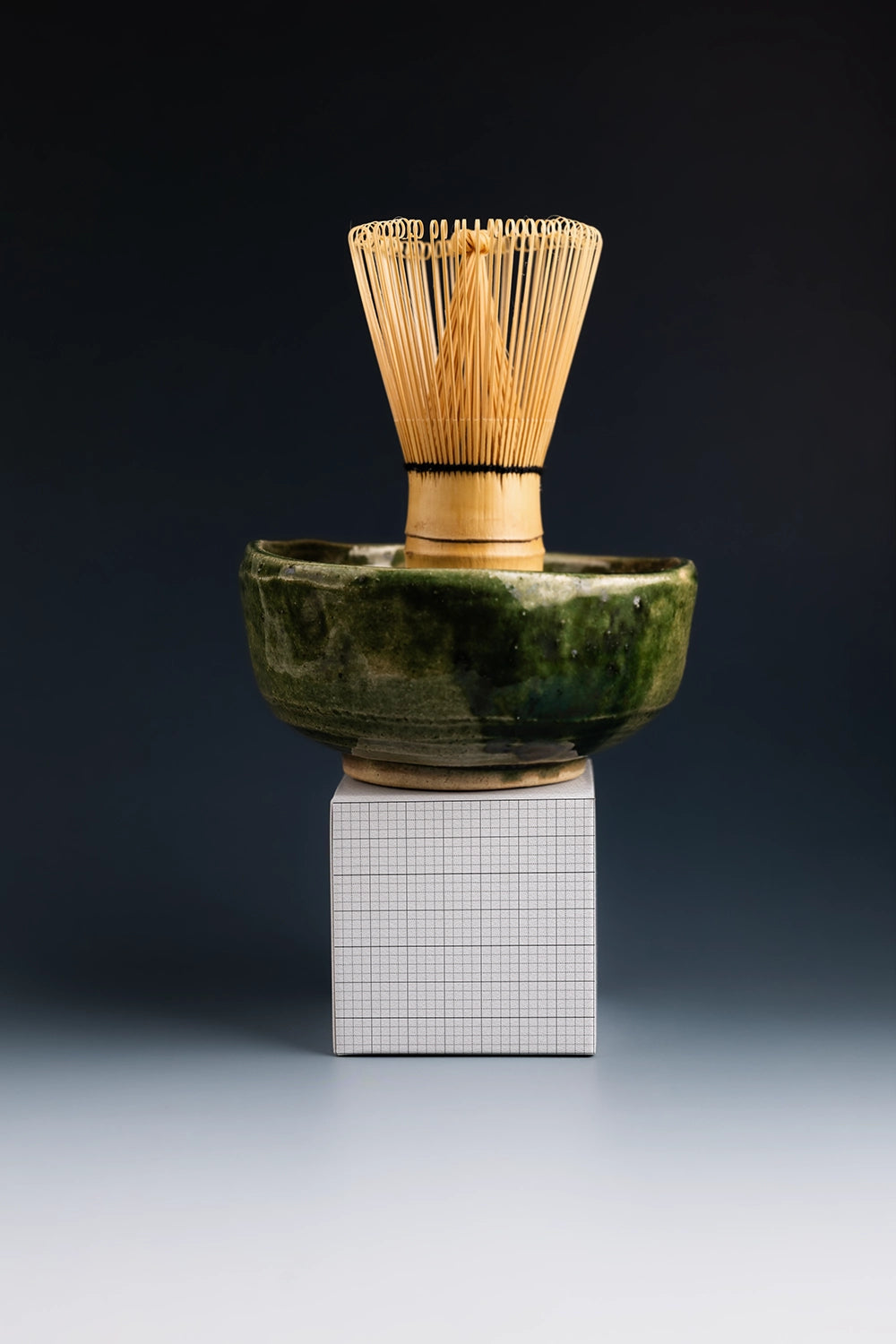 tea packaging box mockup with matcha whisk and bowl on dark background, product presentation