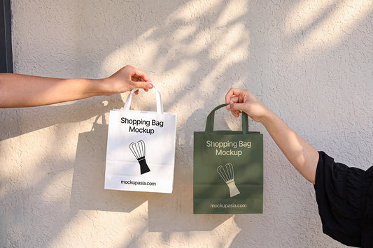 Paper shopping bag mockup PSD held by hands against sunlit wall
