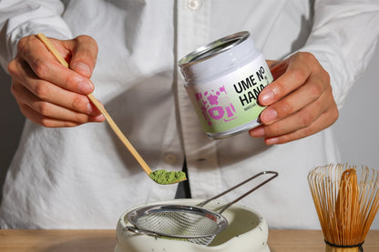 matcha powder jar mockup held in hands with spoon, realistic tea preparation scene