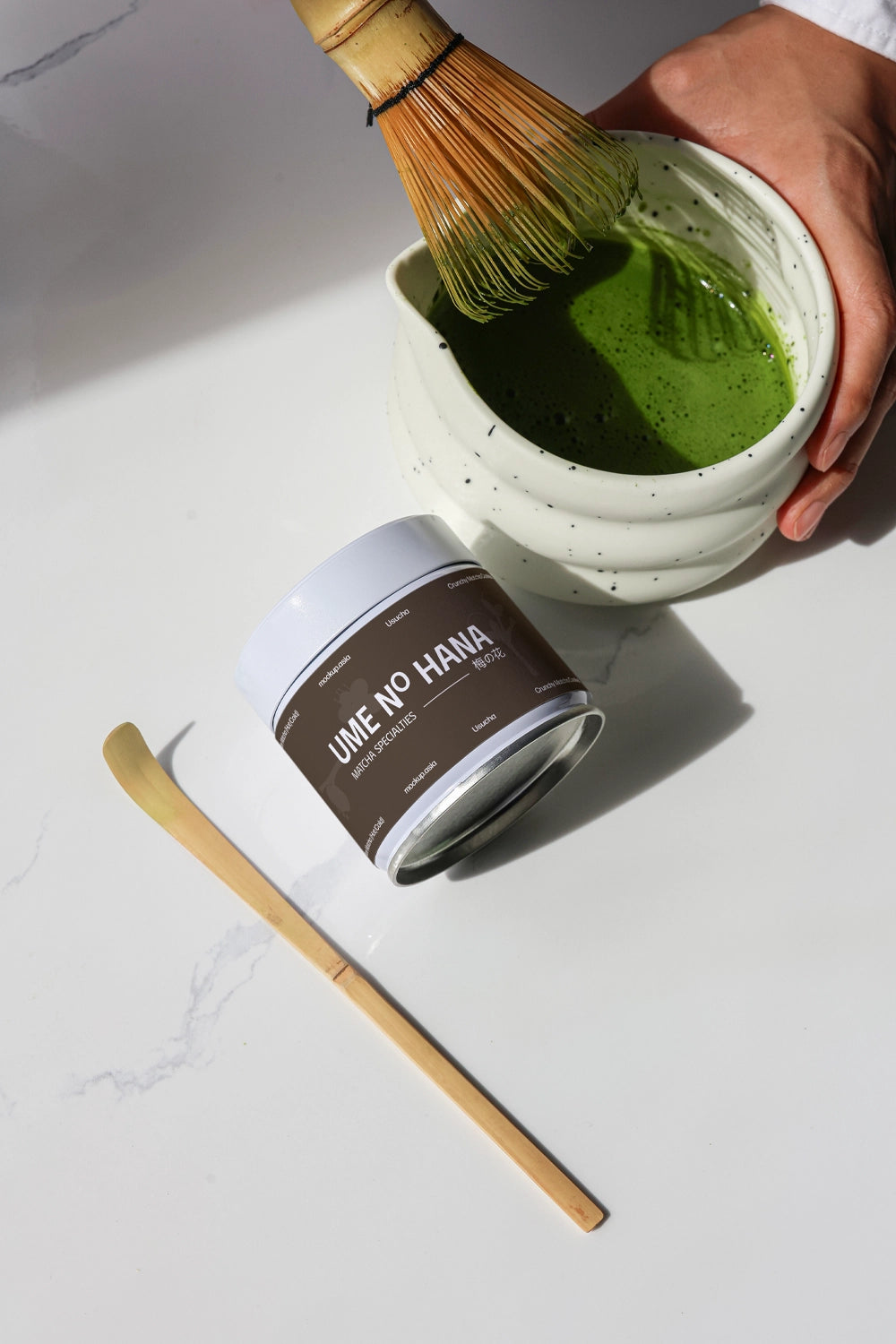 green tea matcha mockup with whisk action and jar, clean flat lay food preparation scene