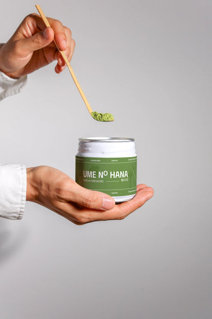 matcha tea packaging mockup with powder scoop above jar, clean hand-held presentation