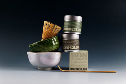 Premium matcha tin can mockup with stacked metal cans, ceramic matcha bowl, bamboo whisk, and dark studio background