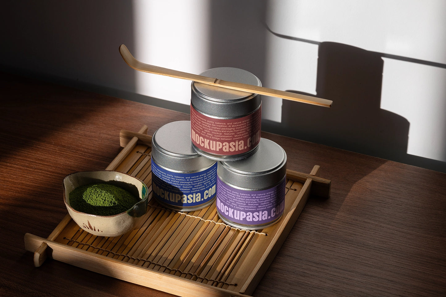 Japanese-inspired matcha product scene with silver tea tins, bamboo serving tray, matcha powder, and whisk