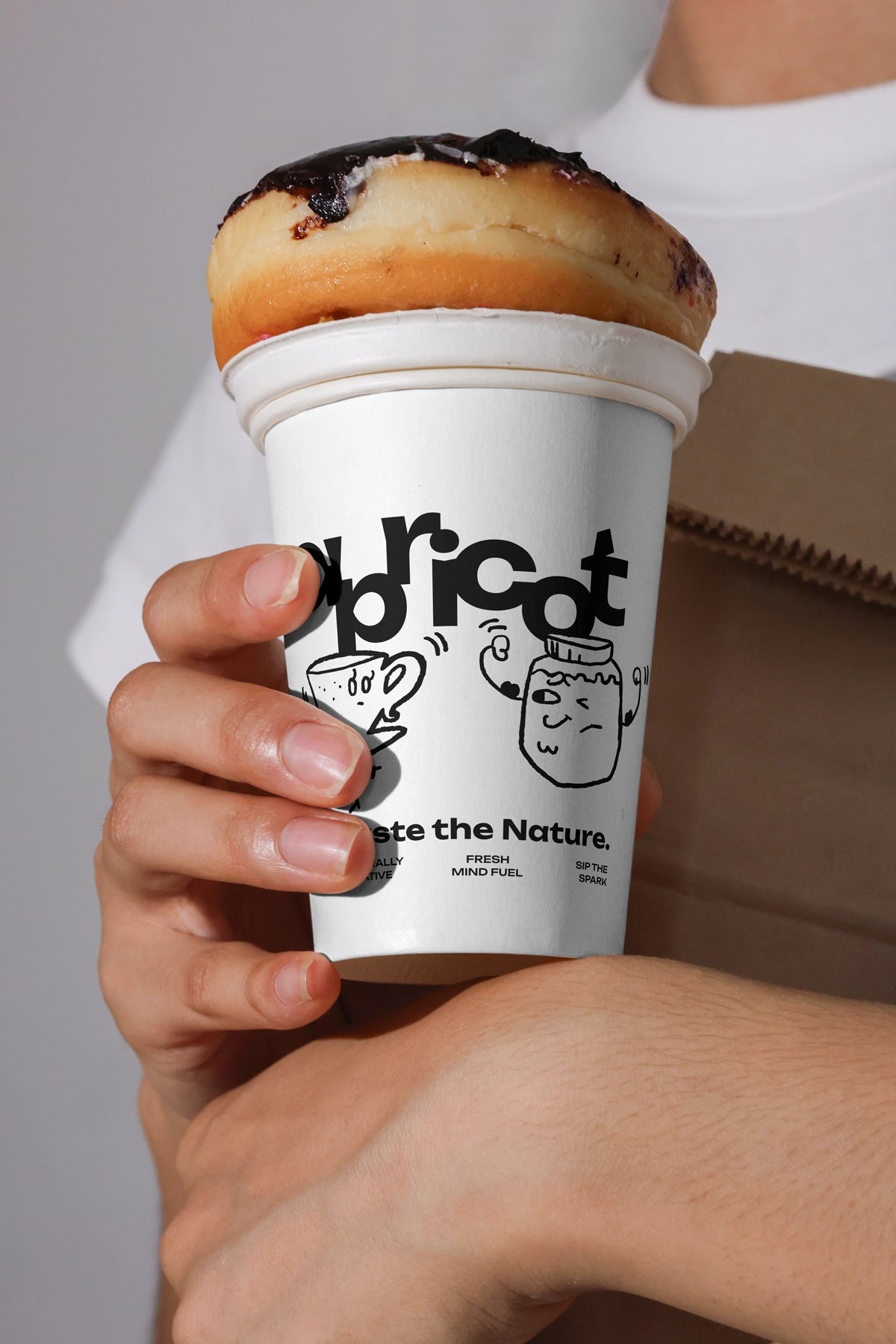 paper coffee cup mockup held in hand with pastry on top, creative cafe branding presentation