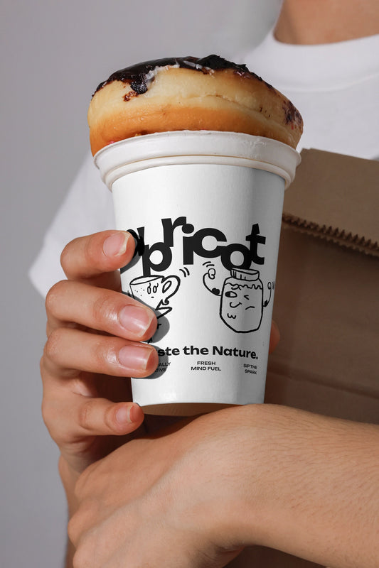 paper coffee cup mockup held in hand with pastry on top, creative cafe branding presentation