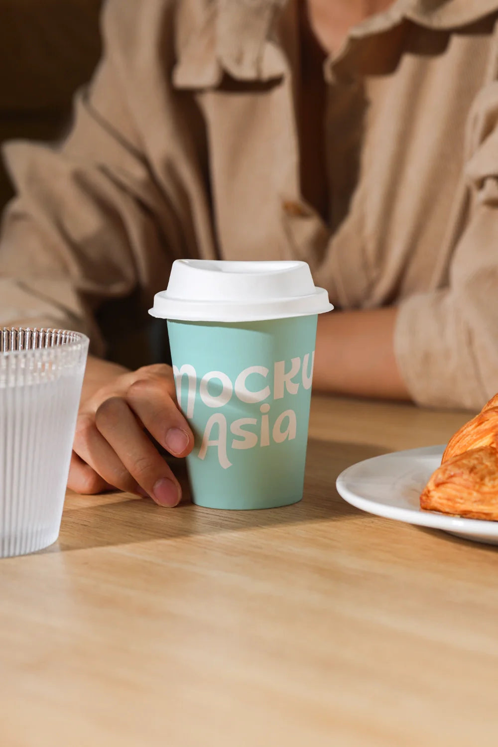 paper coffee cup mockup with hand on wooden table, realistic cafe environment