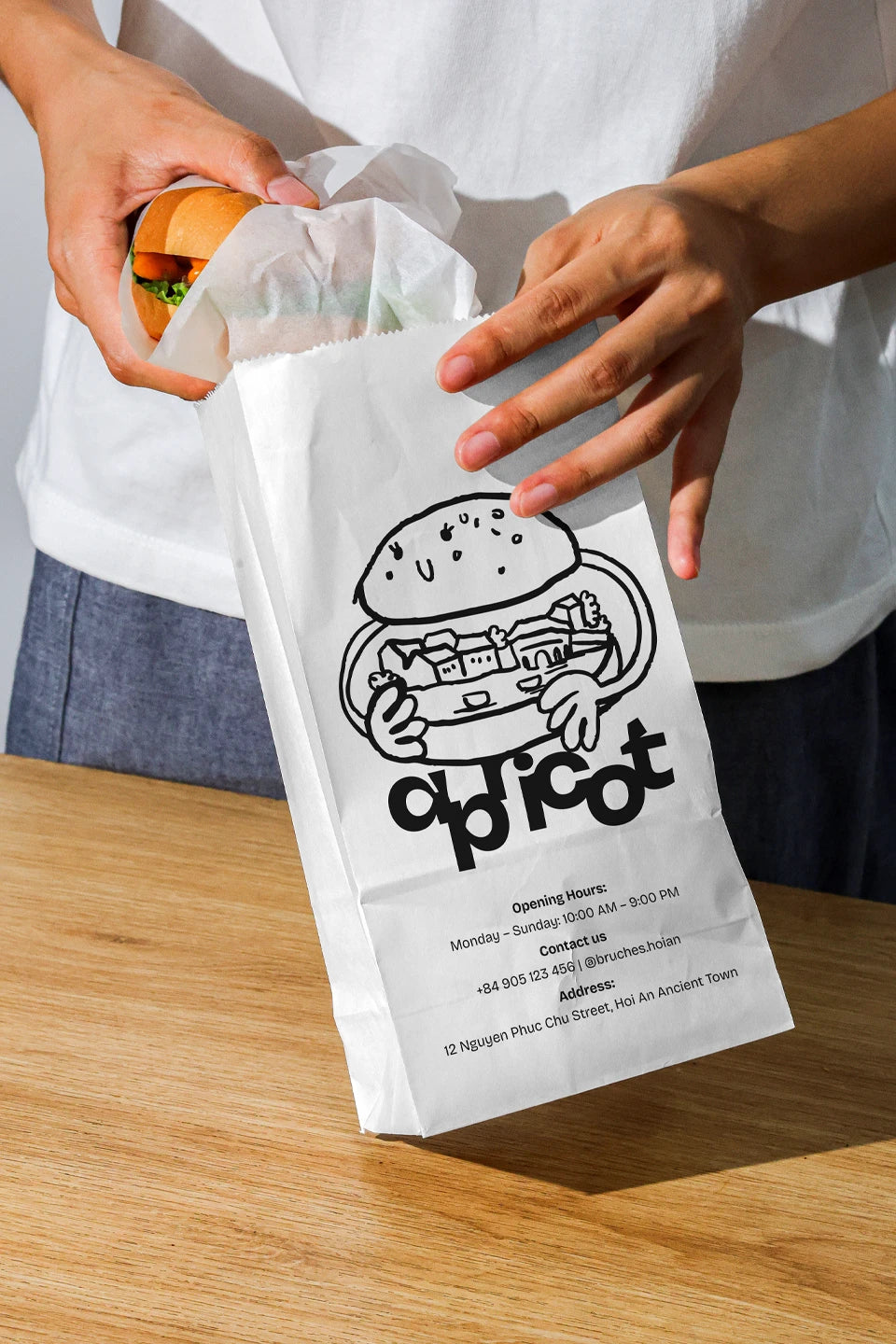 paper food bag mockup with burger inside held by hands, takeaway packaging branding scene