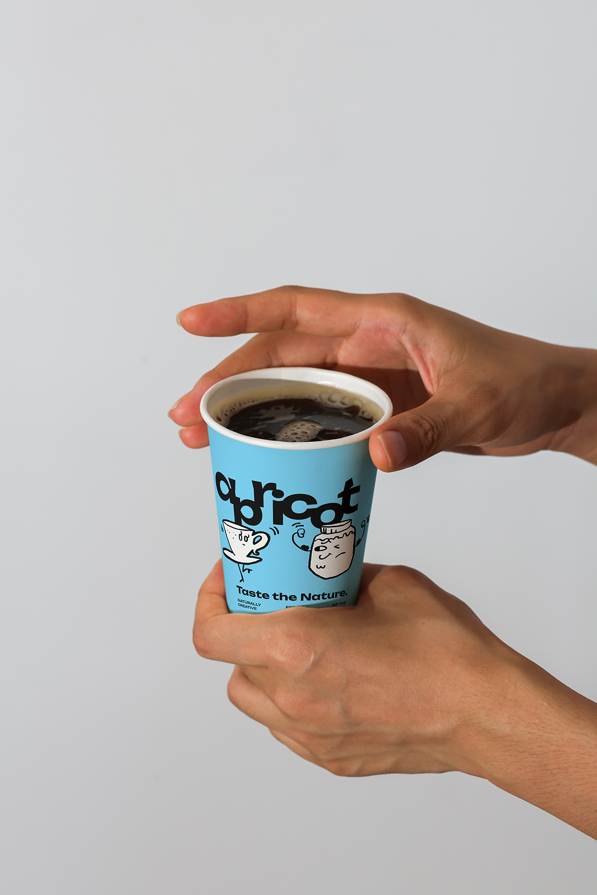 Paper coffee cup with Apricots Coffee Collection bundle label from Mockup.Asia, featuring a printed design on the cup.