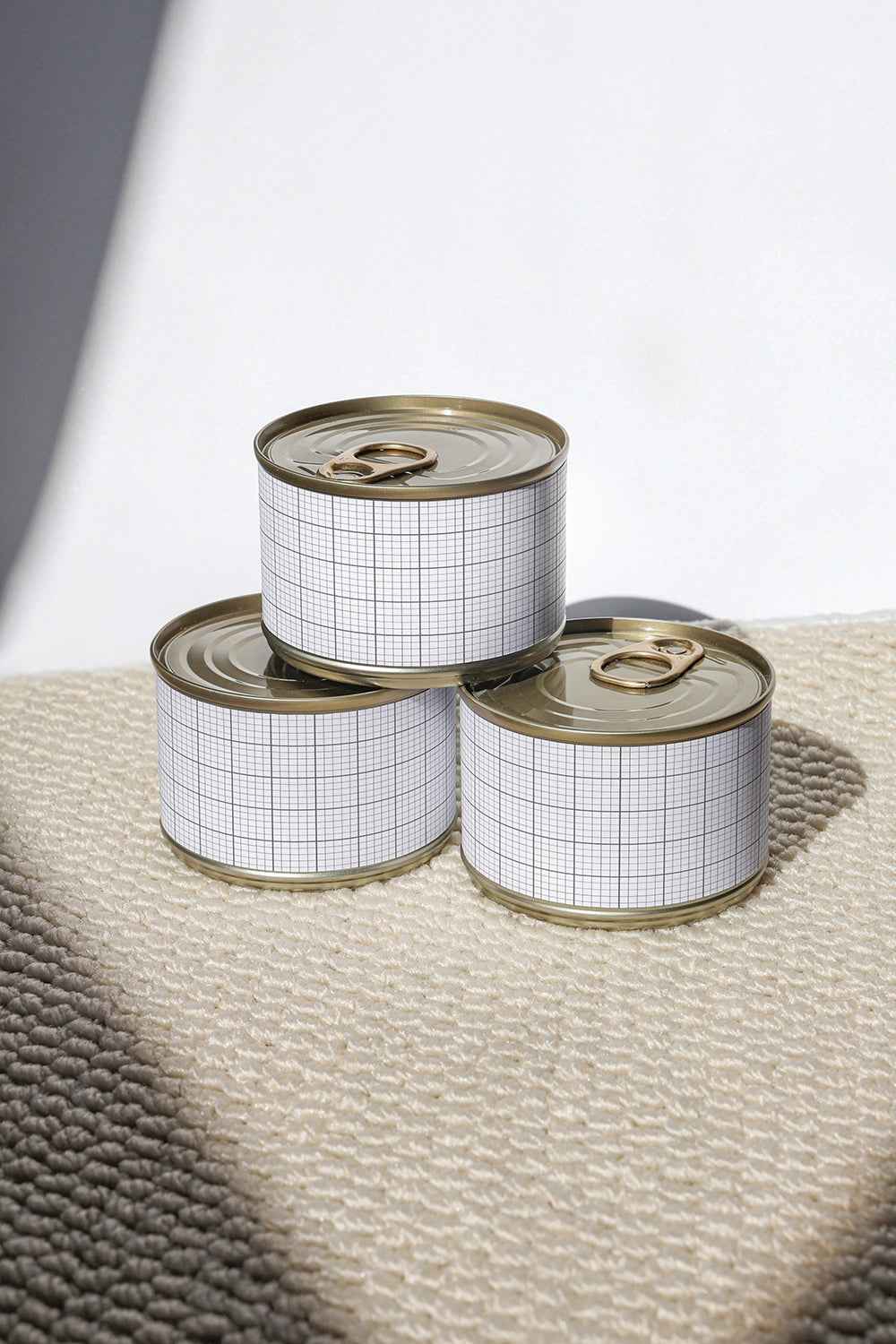 food jar mockup with three cans arranged on textured surface with natural shadows
