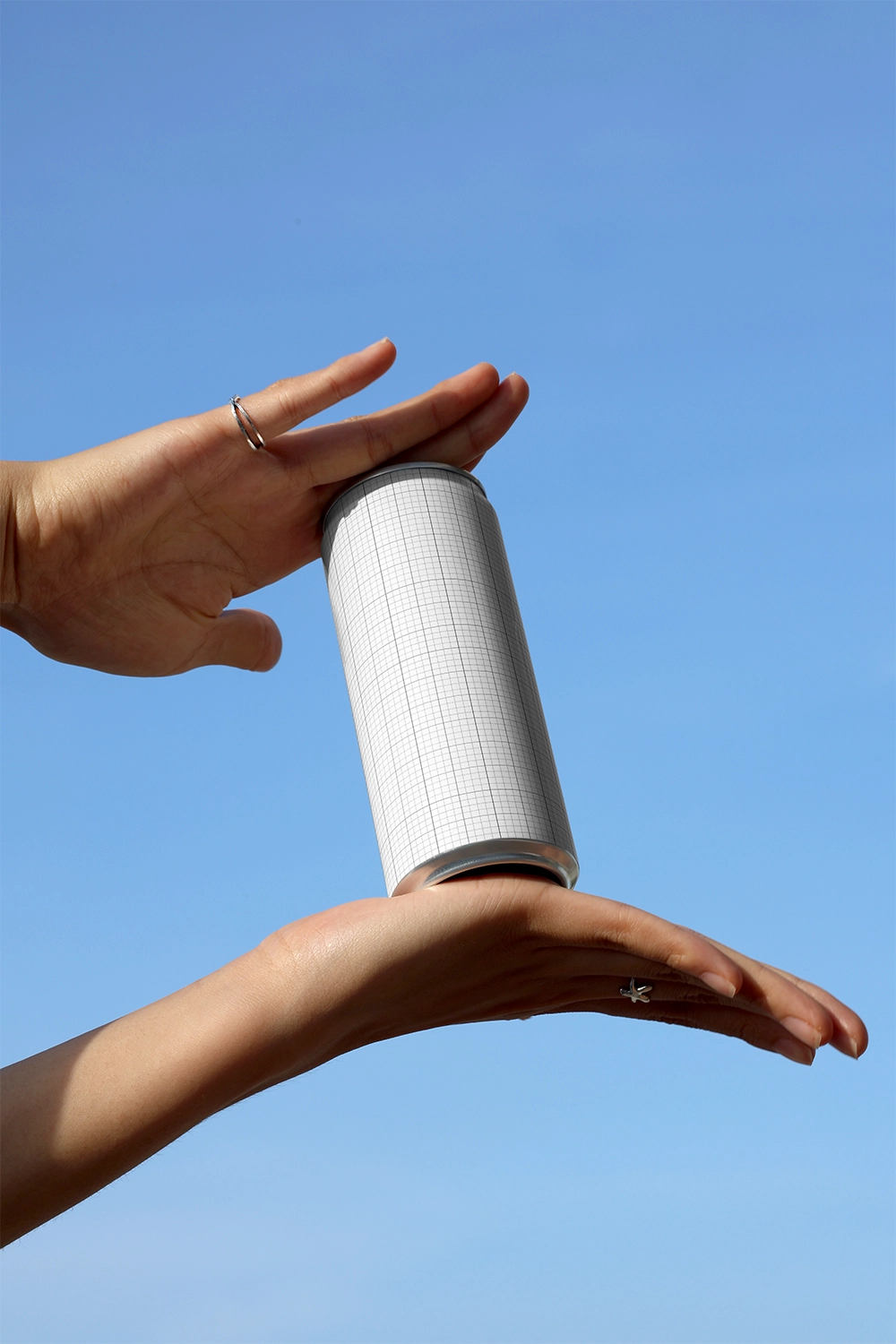 Aluminum soda can mockup in hand with clean sky backdrop for energy drink and juice branding