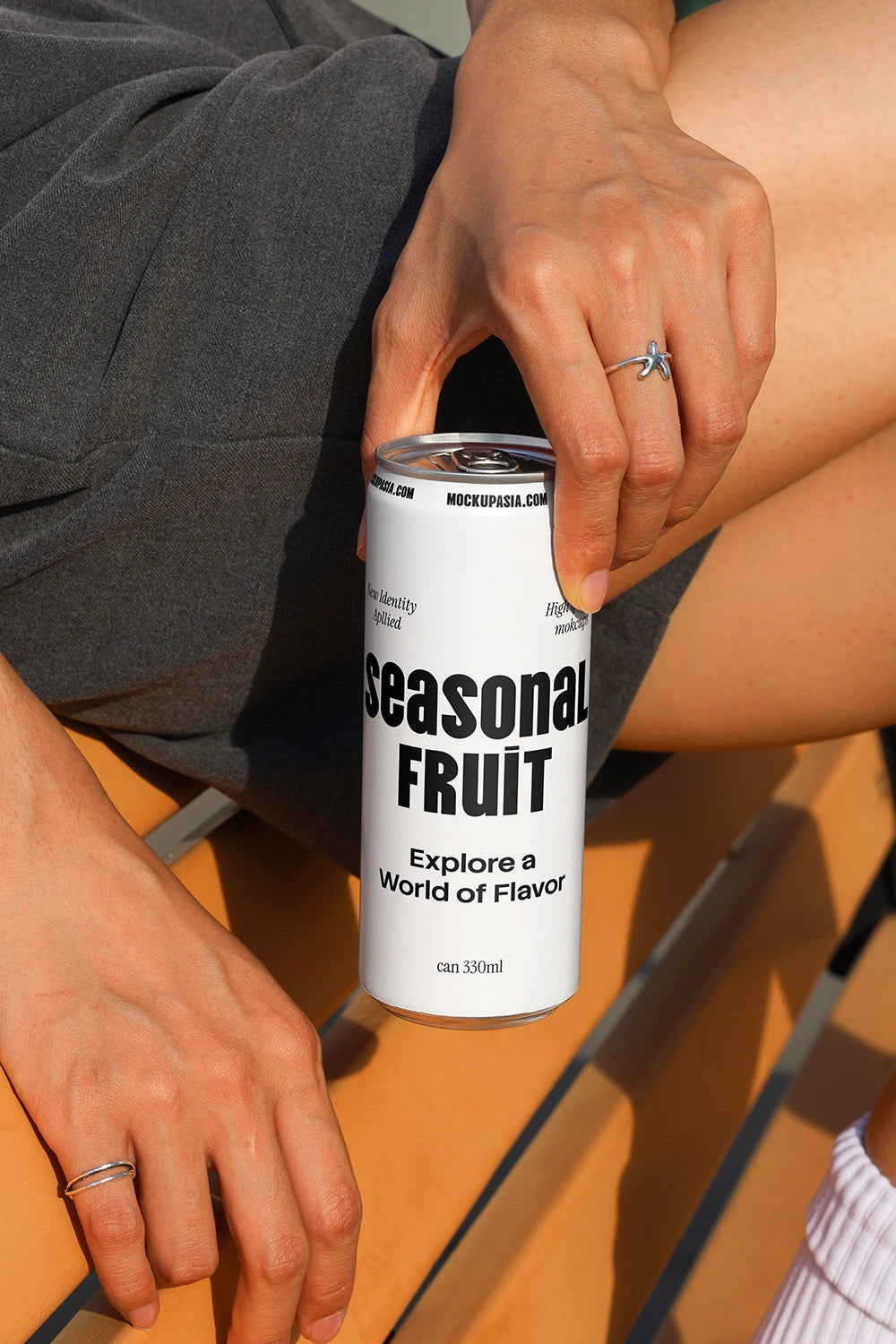 Close-up soda can mockup held by hand on outdoor bench with natural sunlight and shadows