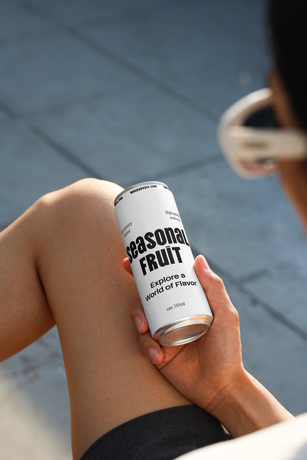 Soda can mockup held on lap in relaxed outdoor setting with natural sunlight and lifestyle composition