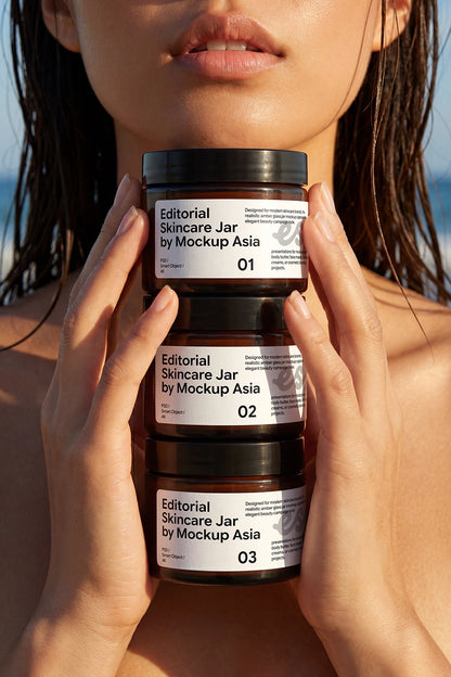 Three stacked amber skincare jars held in front of a beauty model for editorial packaging presentation.