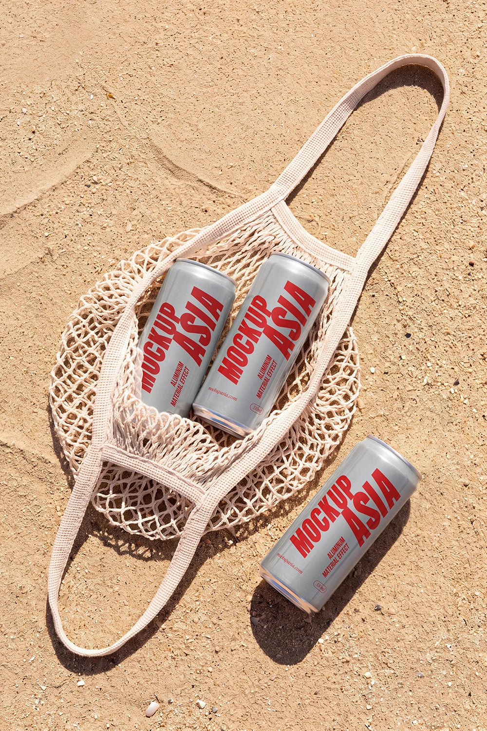 Three realistic aluminum sleek cans mockup in a mesh tote bag on sand