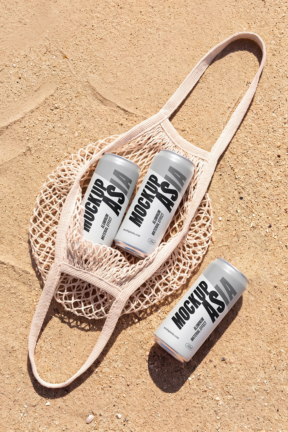 Three realistic aluminum sleek cans mockup in a mesh tote bag on sand