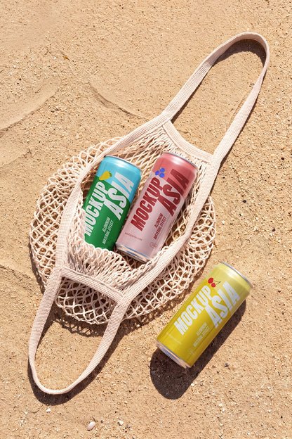 Realistic beverage cans inside a mesh bag with sandy background