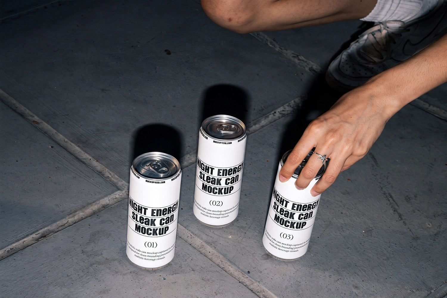 Three slim aluminum cans arranged on urban concrete pavement in a lifestyle mockup.