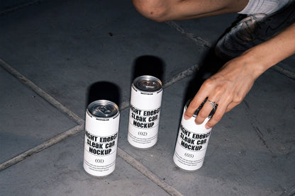 Three slim aluminum cans arranged on urban concrete pavement in a lifestyle mockup.